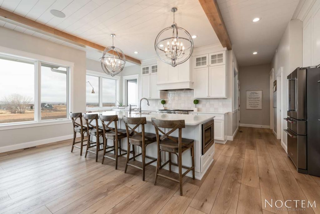 Interior of open concept kitchen with white shiplap ceiling and white cabinets