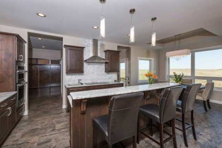 Interior of open kitchen with dark brown cabinets and gray granite