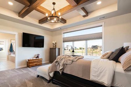 Master bedroom with custom wood finishes and a complimentary chandelier on the ceiling